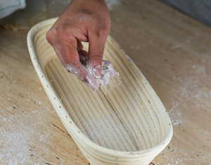 Brotform mit Hand mit Mehl